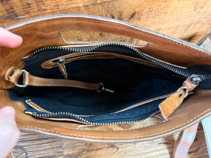 Open tan leather bag interior with navy lining and zip closure