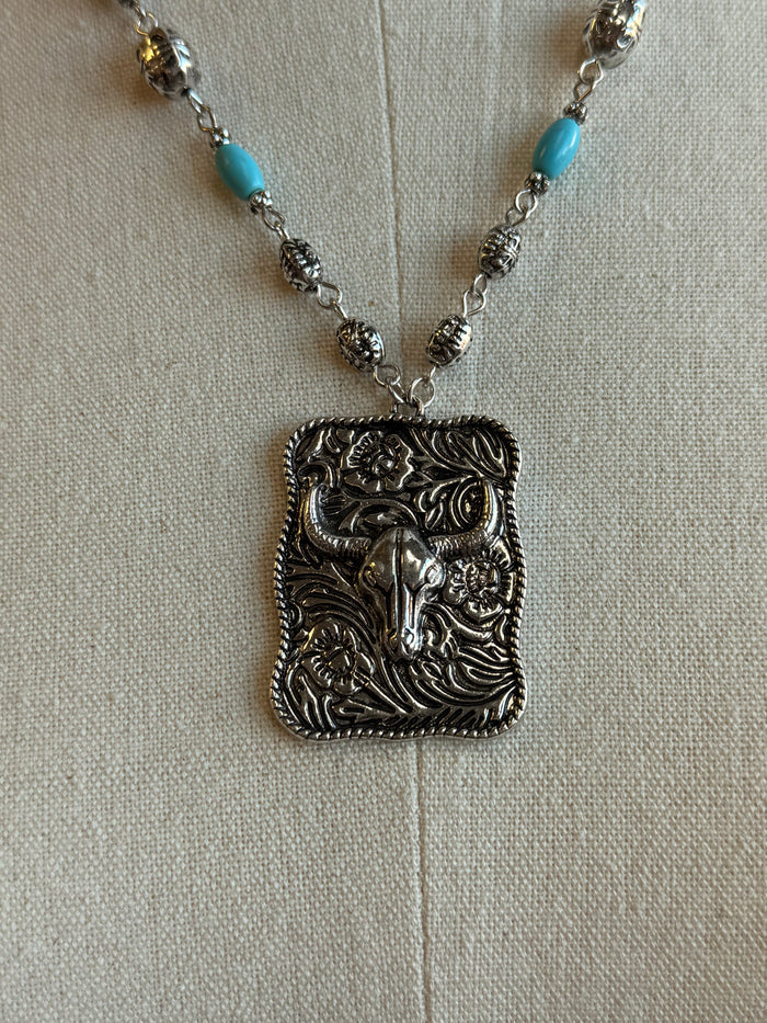 Ornate cowskull pendant with turquoise bead stations on a silver chain