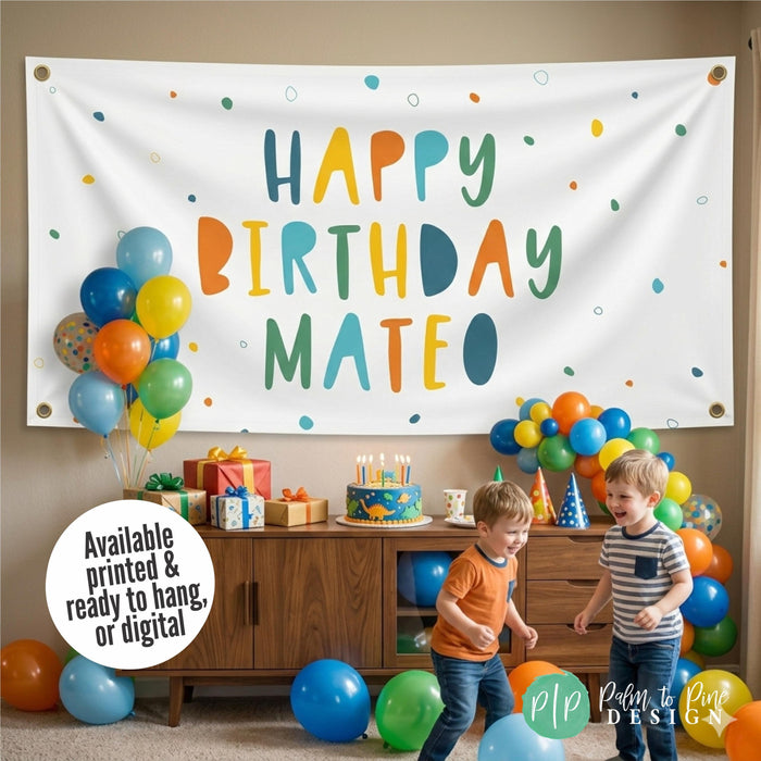 boys birthday party with large personalized banner hung on the wall in blue, green, orange and yellow with toddlers playing in foreground