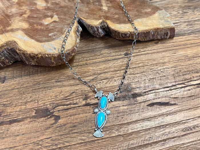 Turquoise cabochon necklace with decorative oval pendant and silver chain links