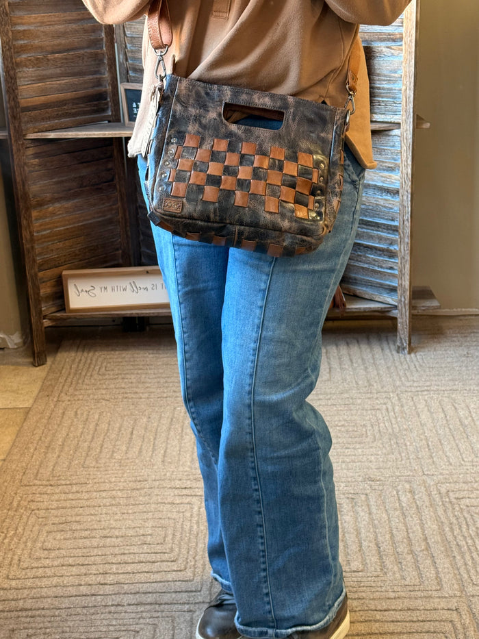 Blue crossbody bag with tan checkerboard front worn with brown leather strap