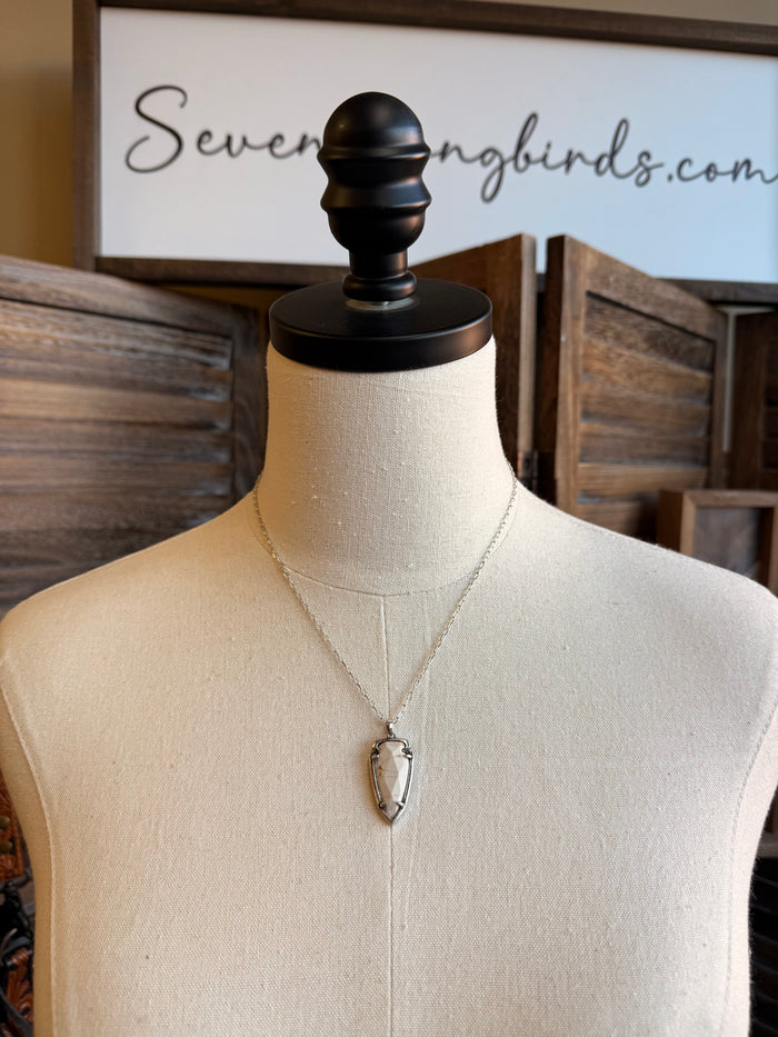 Gold-tone arrowhead pendant necklace with white faceted stone on thin chain