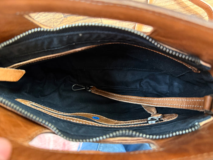 Open top crossbody bag interior with black lining, zipper, and stitched leather trim