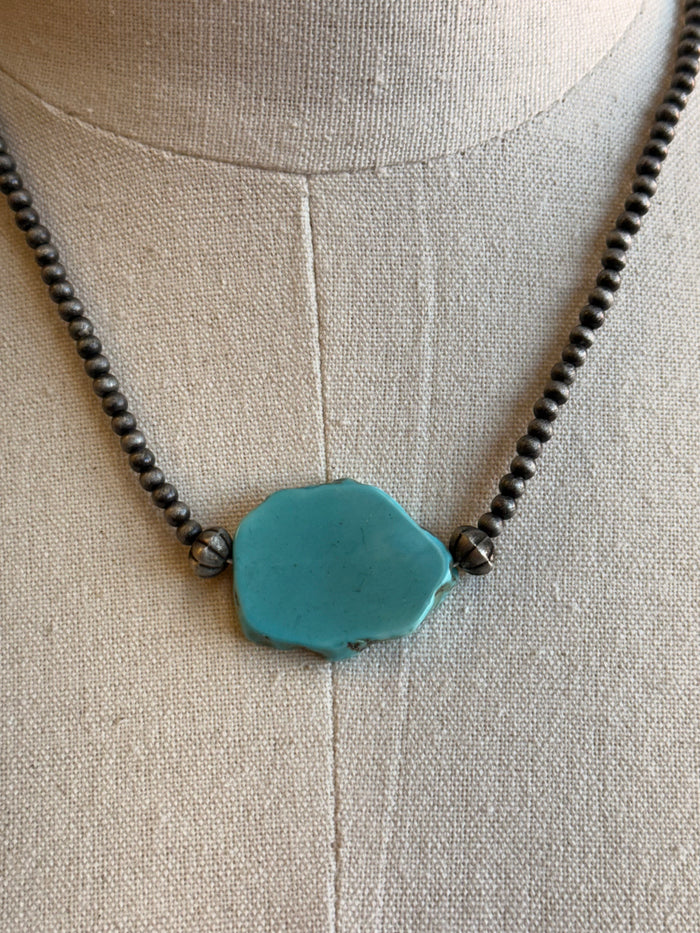 Turquoise chunk pendant necklace close-up with teal pendant on dark bead chain