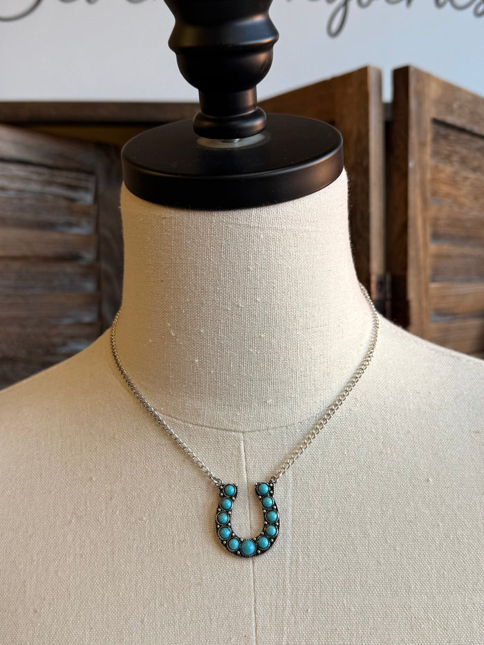 Turquoise horseshoe necklace on mannequin with silver chain and dangling U-bead pendant