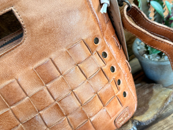 Keiki tan leather bag corner with woven panel texture and metal rivet accents