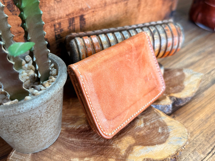 Tan leather wallet front flap close-up, angled view