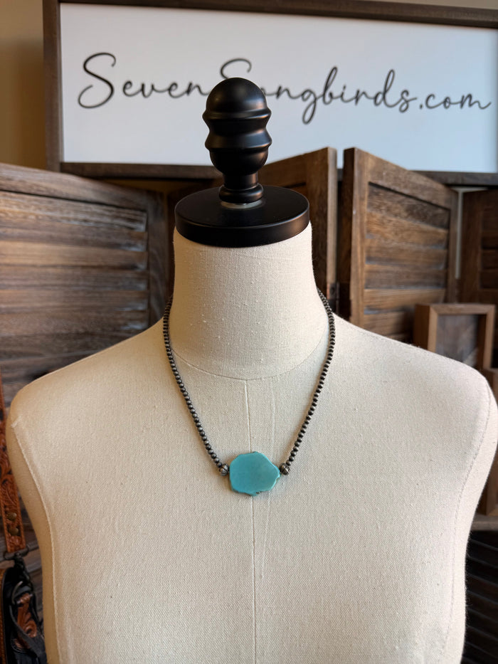 Turquoise chunk pendant necklace with dark chain on a mannequin bust