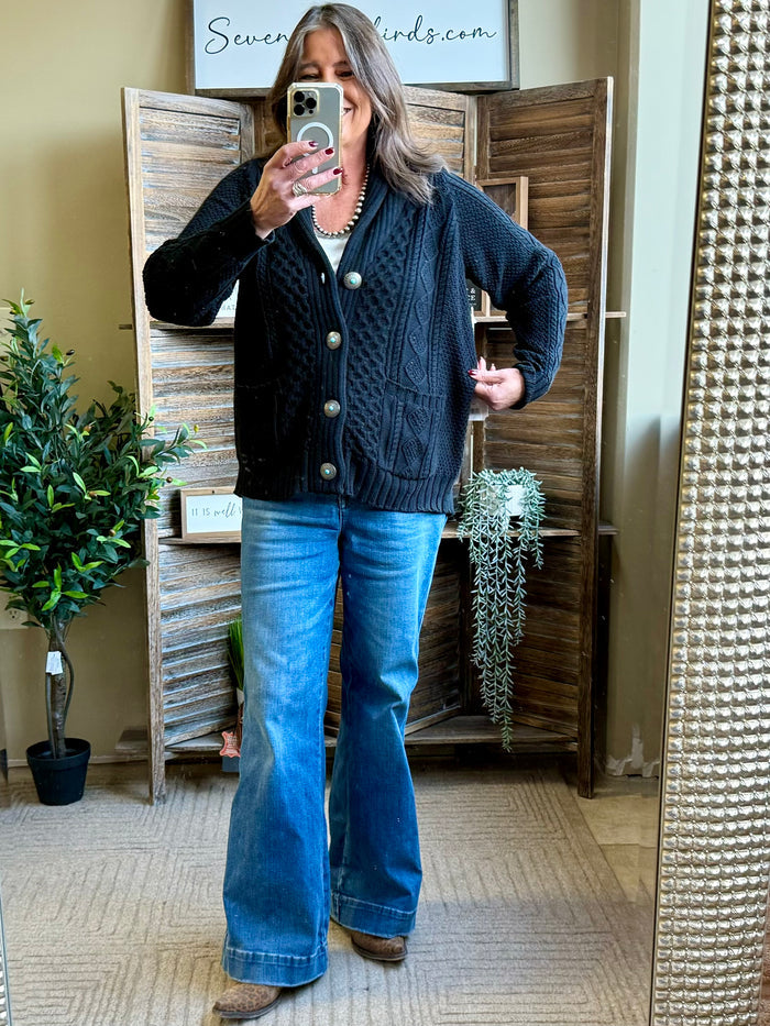 Dark cable-knit cardigan with long sleeves, round gold-tone buttons, and ribbed trim