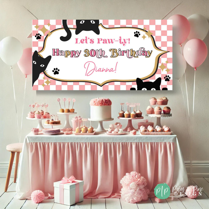 pink and gold cat birthday party decoration showing a custom vinyl banner with cat motif, pink and gold color scheme, with black cats and text reading 'Let's Paw-ty! Happy Birthday