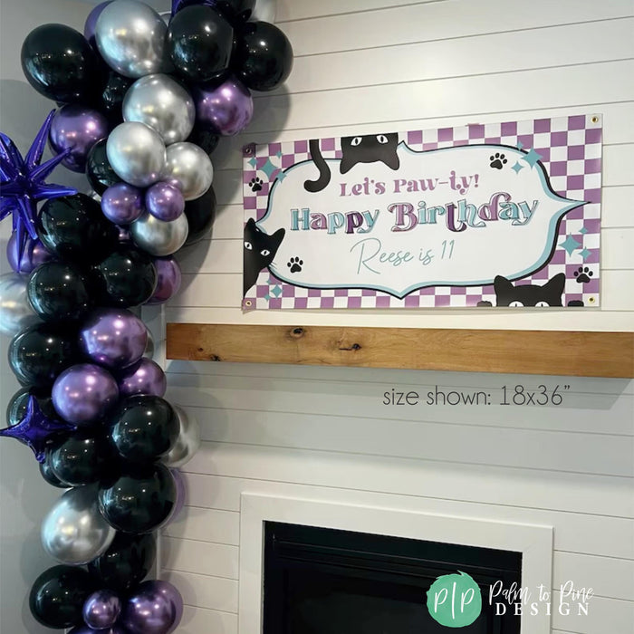 Cat-themed birthday vinyl banner for Reese's 11th birthday with 'Let's Paw-ty!' text, purple checkered border, playful black cat illustrations, and teal accents, displayed on a white shiplap wall with a purple, silver and black balloon garland.