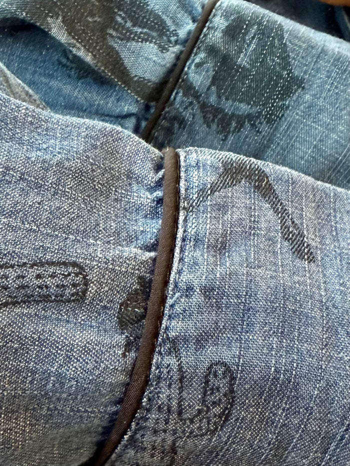 Detail of blue denim snap-front shirt placket and yoke seam with dark western print