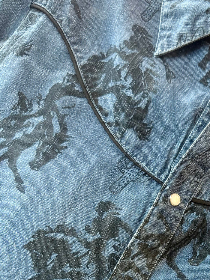 Close-up of blue denim snap-front shirt collar with dark western print and metal snap