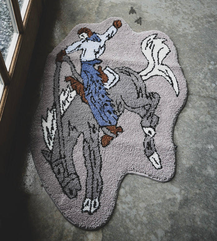 Bronc rug with stitched horse-and-rider illustration in gray and blue details