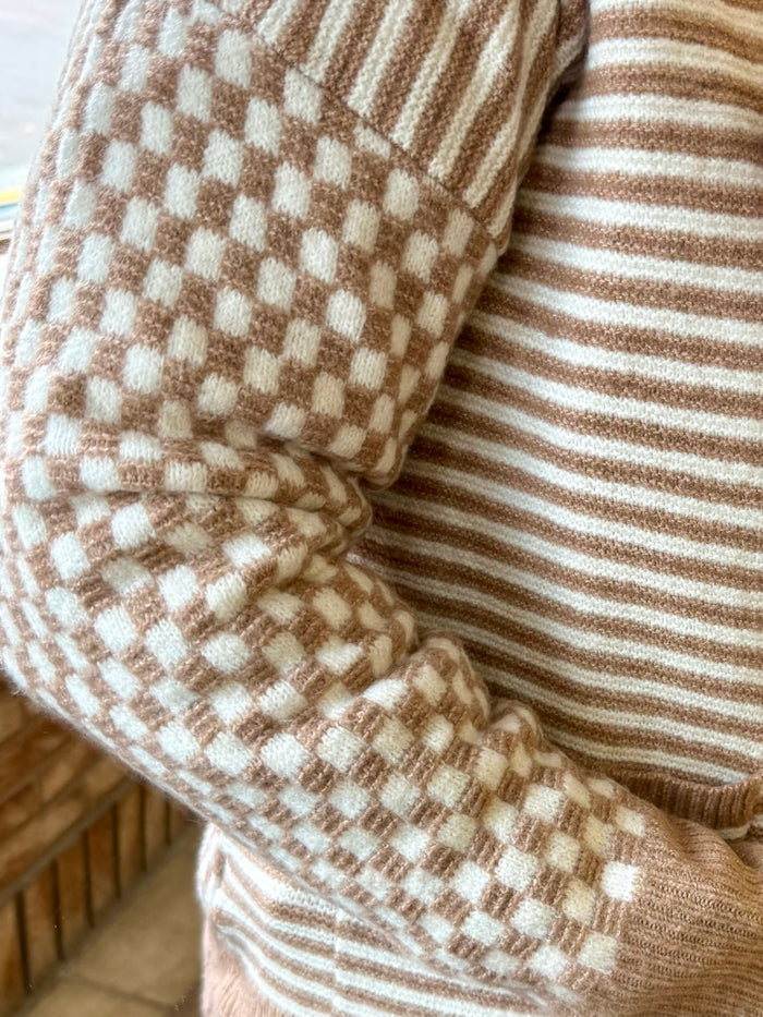 Checkerboard knit sleeve cuff detail with striped fabric panel on side.