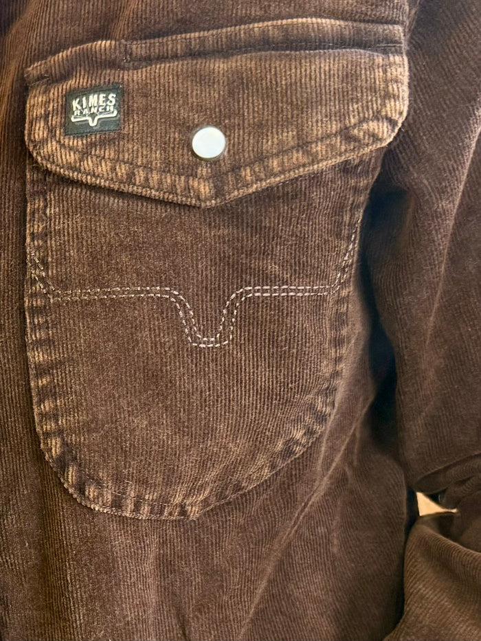 Dark brown corduroy shirt chest pocket with stitched seams and brand label