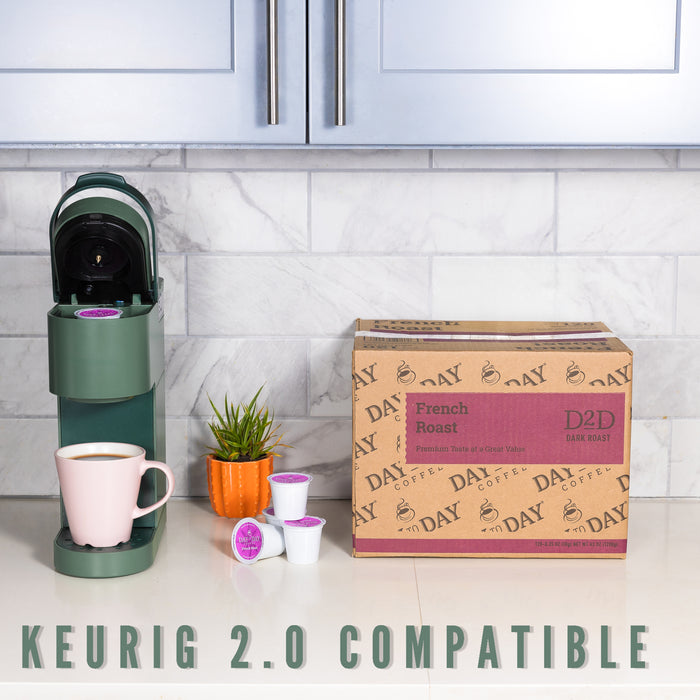 Keurig 2.0 compatible coffee maker with coffee pods and a box of Day by Day coffee on a kitchen counter.