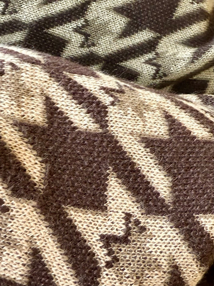 Close-up knit texture of brown-and-cream houndstooth horse-pattern cardigan fabric