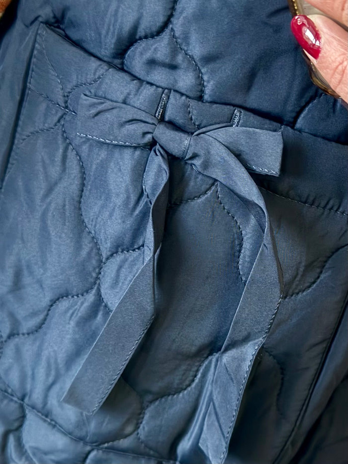 Quilted navy puffer vest with front zipper and bow-tie seam detail