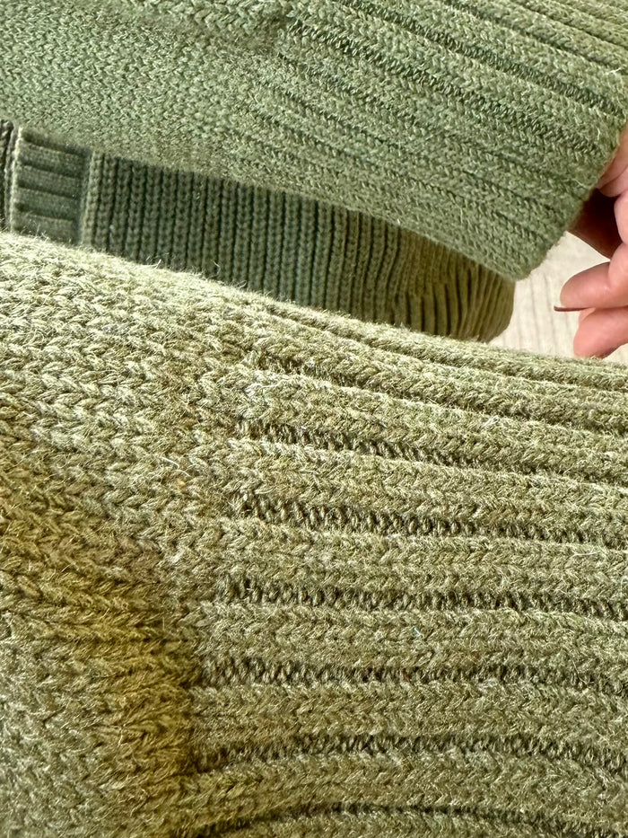 Olive green sweater cuff and hem with ribbed knit and cable stitch texture