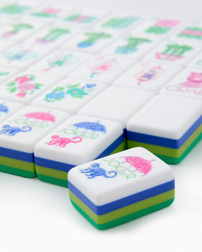 Stack of white mahjong tiles with green and blue border stripes and colorful printed symbols
