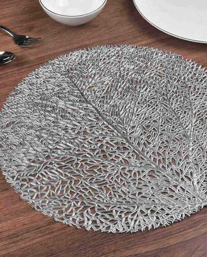 Silver round metallic placemat with dense woven filaments, visible leaf pattern