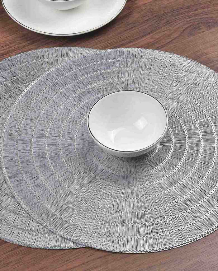 Silver round textured placemat with concentric loop rings, set under a dish