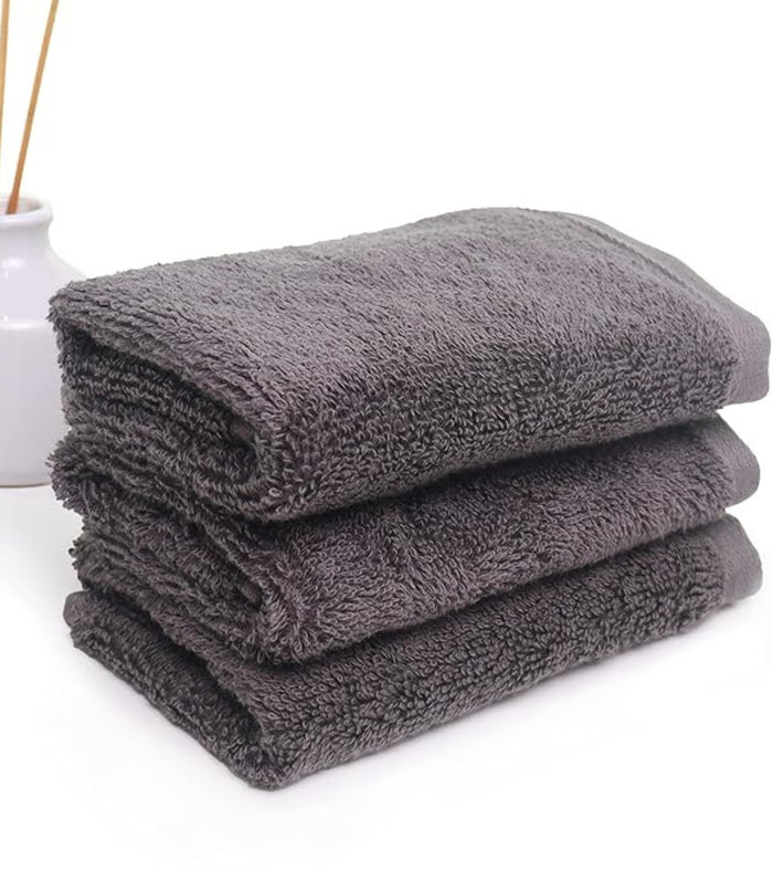 Set of three grey plush hand towels, neatly folded stack