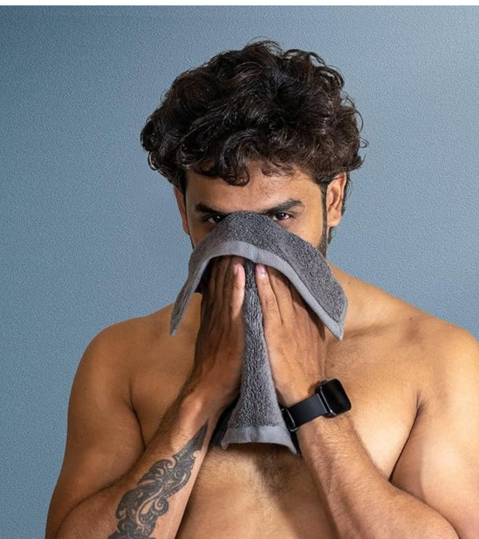 Grey plush towel held to dry a person’s face and chest