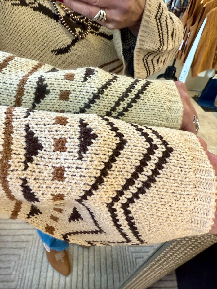 Tan knit sweater sleeve with black, brown, and cream Fair Isle geometric motif.