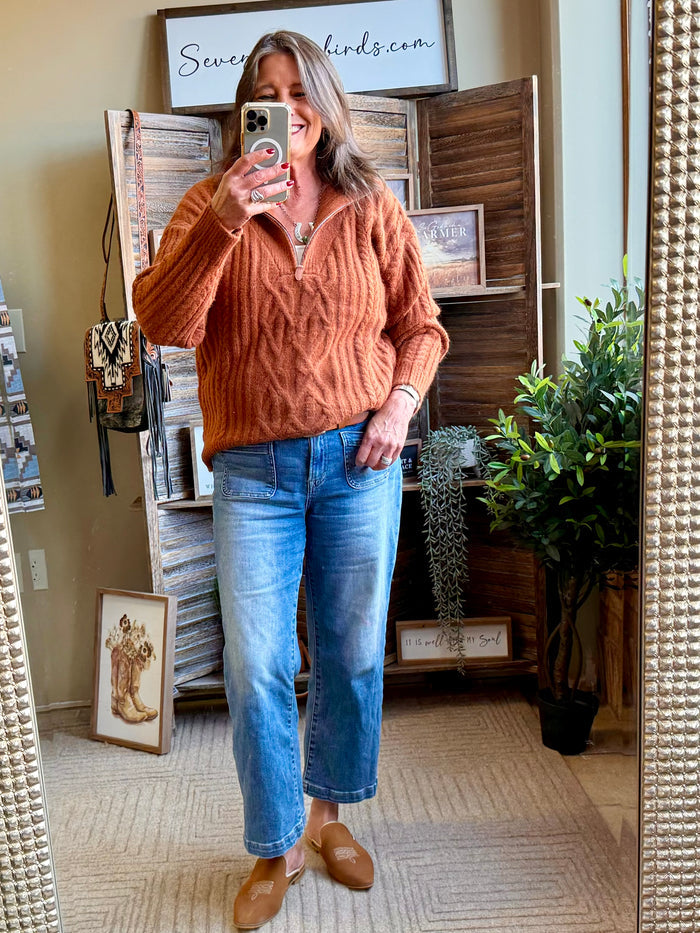 Rust cable knit 1/4 zip sweater worn with blue jeans