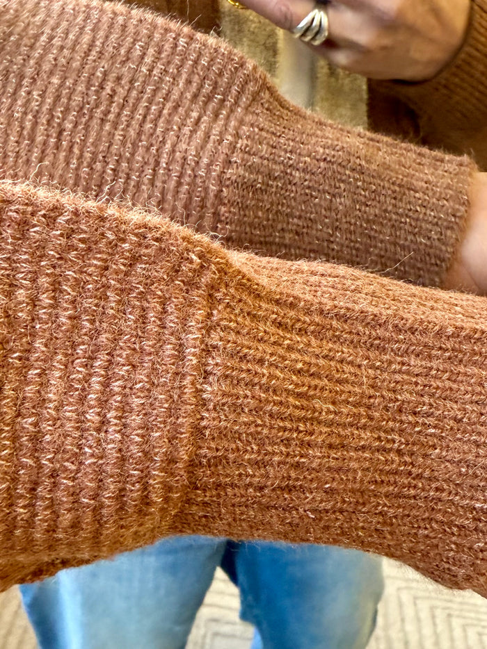 Rust-brown knit cardigan fabric close-up with ribbed sleeve hem and cuff