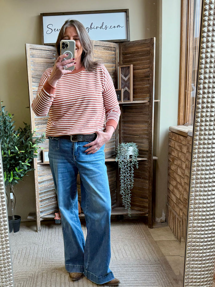 Rust and white striped crew-neck sweater with long sleeves and ribbed cuffs