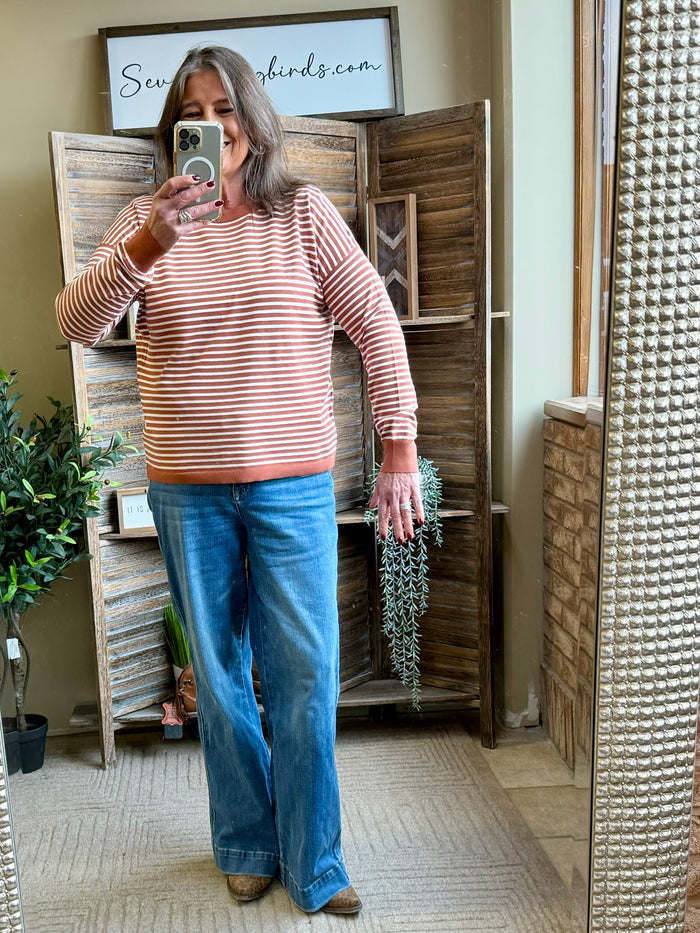 Rust and white striped crew-neck sweater with long sleeves