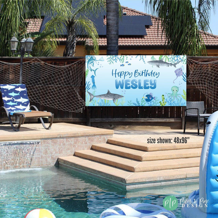 boys shark birthday banner at outdoor party with pool