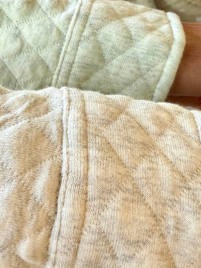 Beige quilted knit fabric detail with raised diamond pattern and vertical seam