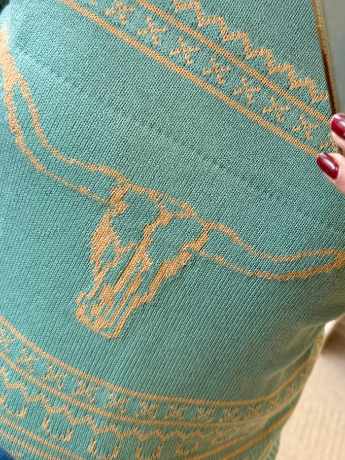 Close-up of turquoise knit sweater with tan longhorn motif and stitched bands