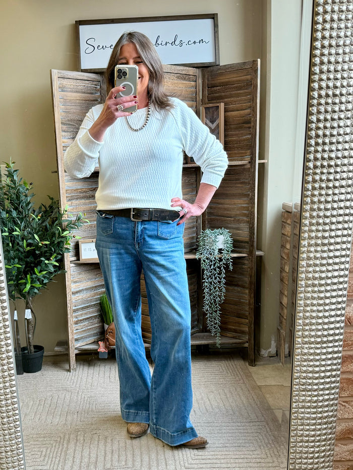 White textured crew neck sweater worn with blue wide-leg jeans