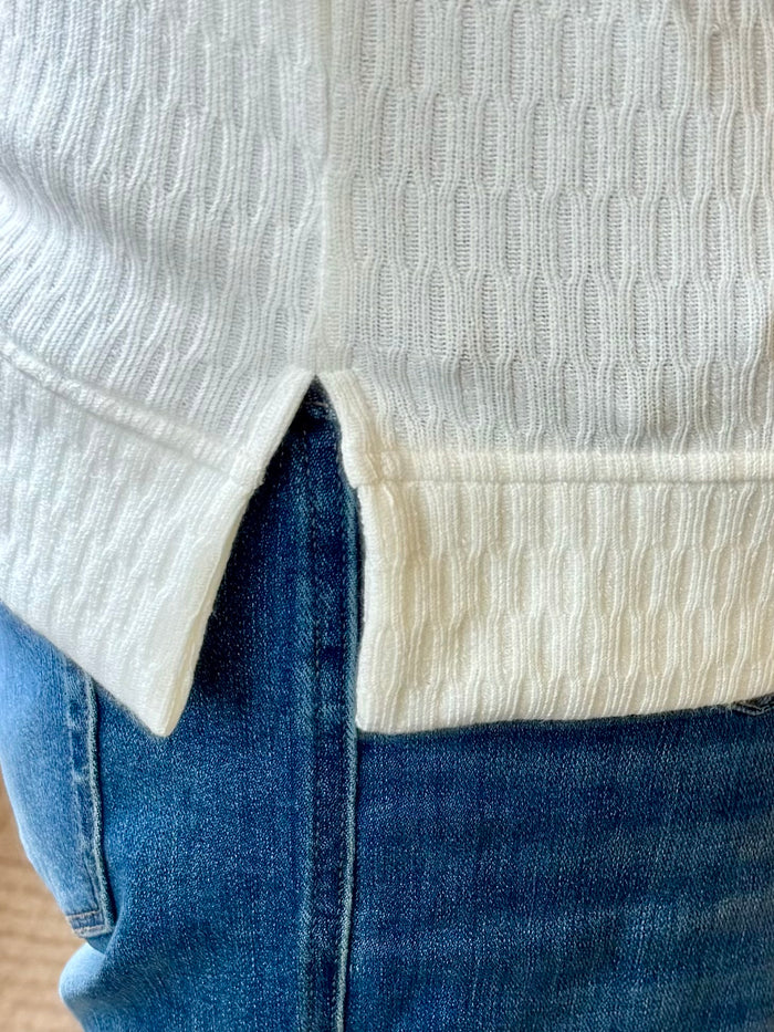 White textured crew neck sweater, ribbed hem and cuff close-up